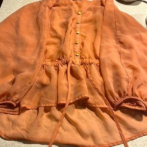 This is an peach colored blouse button up scrunched top with strings